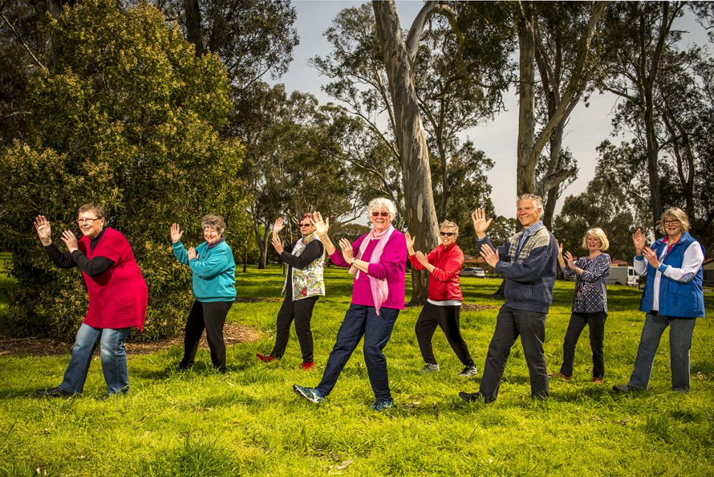 Group of older people practising Tai Chi in a grassy clearing