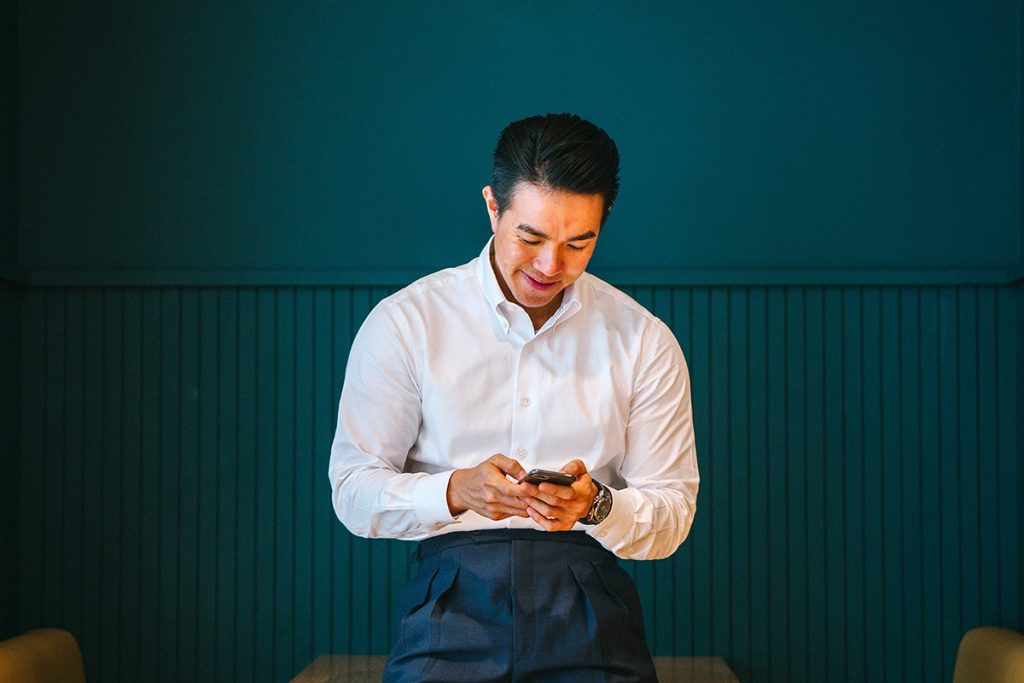 Asian man smiling and looking at his mobile phone