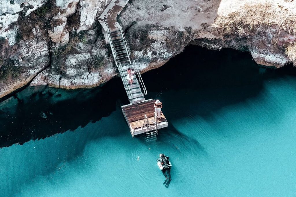 Walk way to blue lake with scuba diver, seen from overhead